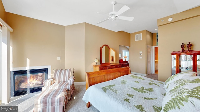 carpeted bedroom with a multi sided fireplace, ceiling fan, and a high ceiling