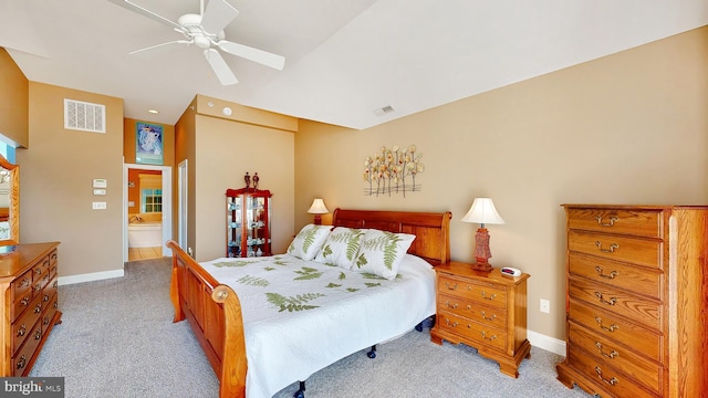 bedroom with ceiling fan, light colored carpet, and ensuite bath