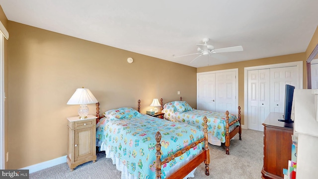 carpeted bedroom featuring ceiling fan and multiple closets