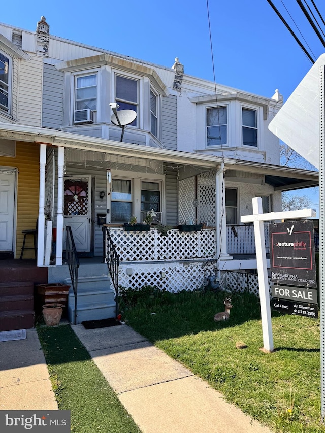 townhome / multi-family property with covered porch and a front lawn