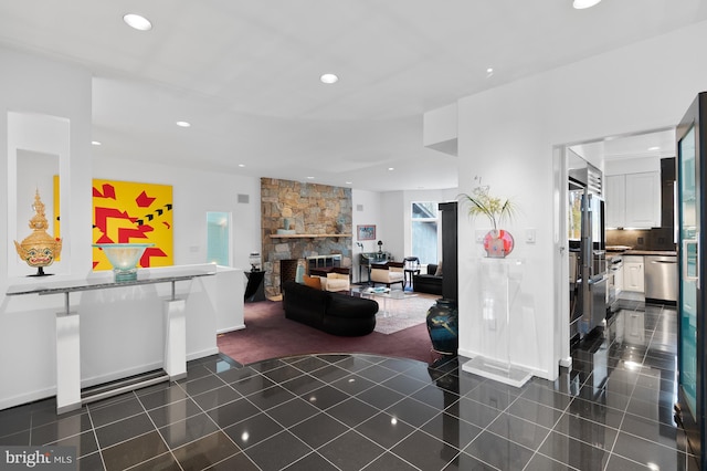 tiled living room featuring a stone fireplace