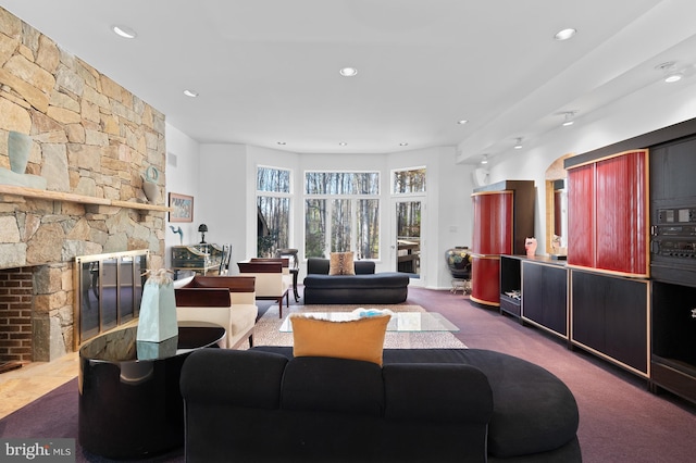 living room with a stone fireplace and carpet