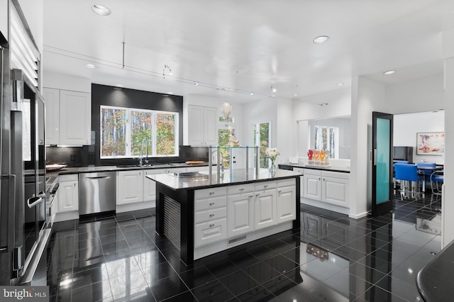 kitchen featuring a kitchen island, dark tile flooring, dishwasher, and white cabinetry