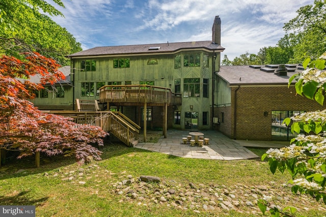 rear view of property with a deck, a lawn, and a patio area