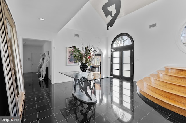 entrance foyer featuring dark tile flooring and a towering ceiling