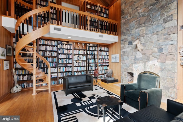 sitting room featuring a high ceiling, hardwood / wood-style flooring, and wood walls