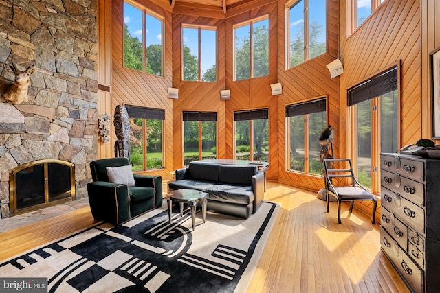 living room featuring wood walls, a towering ceiling, hardwood / wood-style floors, and a fireplace