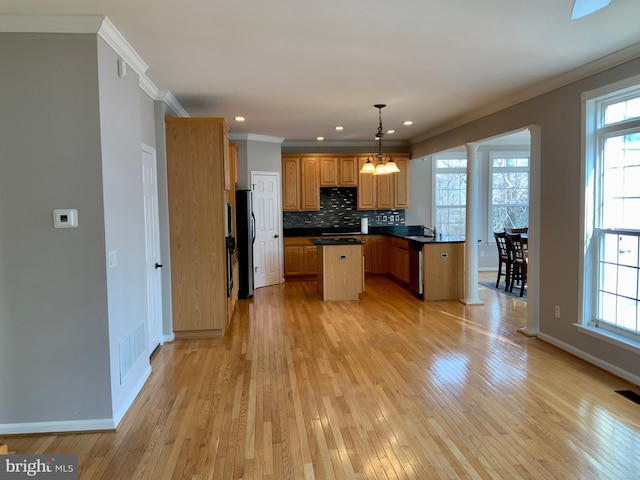 kitchen with dishwasher, black refrigerator, hanging light fixtures, plenty of natural light, and a kitchen island