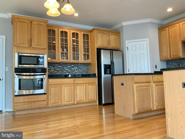 kitchen featuring appliances with stainless steel finishes, a notable chandelier, ornamental molding, and tasteful backsplash