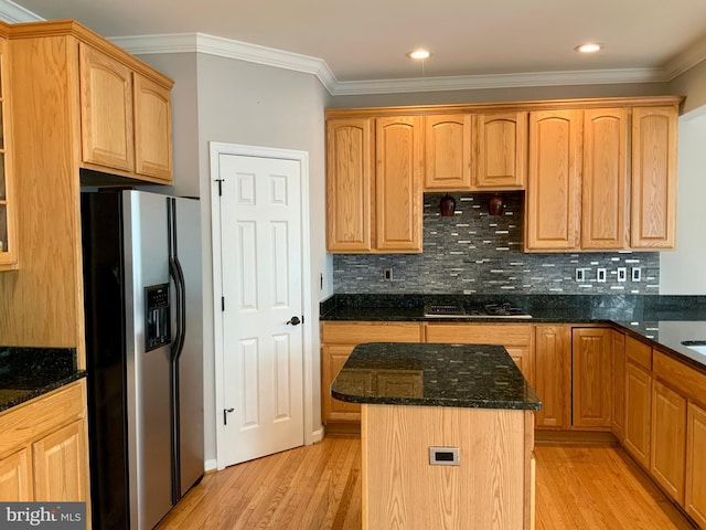 kitchen with dark stone countertops, ornamental molding, a kitchen island, decorative backsplash, and stainless steel refrigerator with ice dispenser