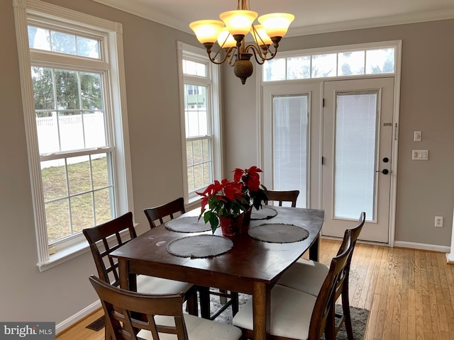 dining room with crown molding, a chandelier, and light hardwood / wood-style flooring