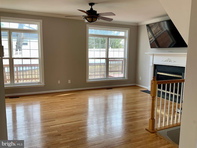 unfurnished living room featuring ornamental molding, ceiling fan, and light hardwood / wood-style flooring