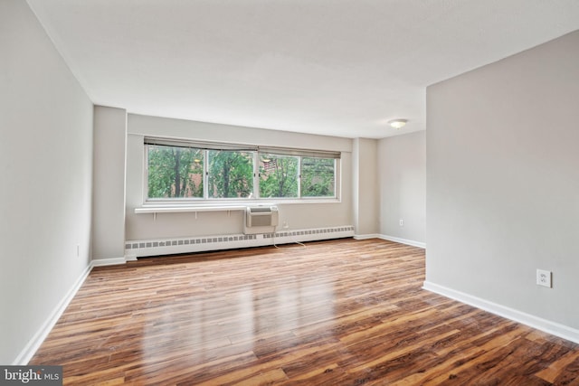 empty room featuring a baseboard radiator, a wall mounted AC, and light hardwood / wood-style flooring