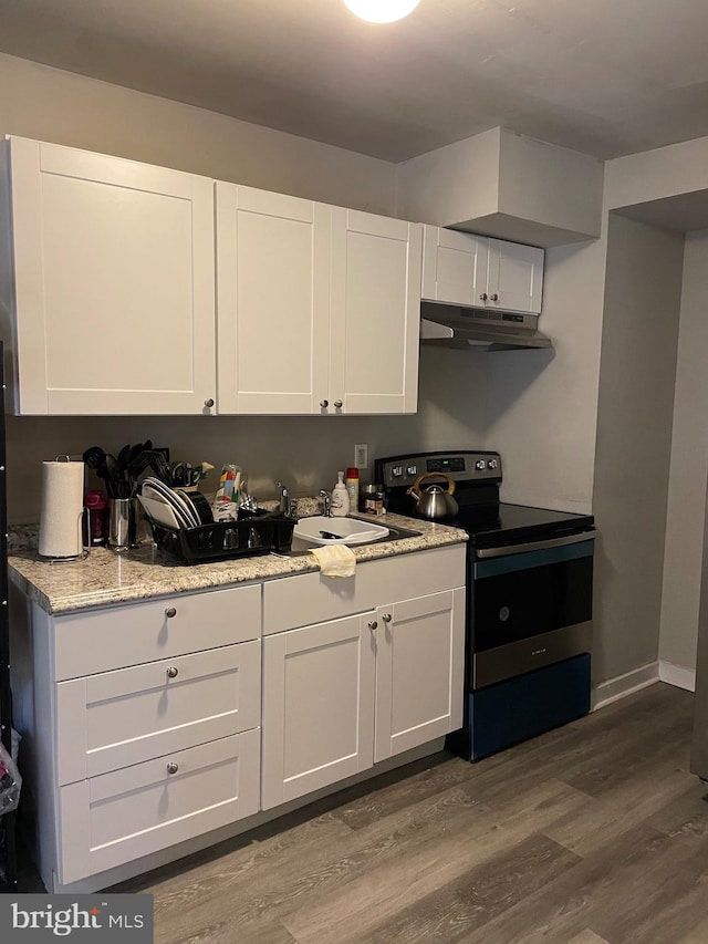 kitchen featuring hardwood / wood-style floors, light stone countertops, range with electric stovetop, and white cabinetry