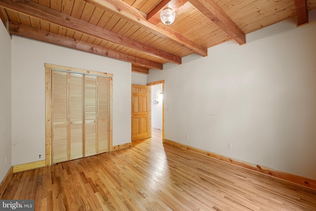 unfurnished bedroom featuring beam ceiling, light hardwood / wood-style floors, a closet, and wood ceiling