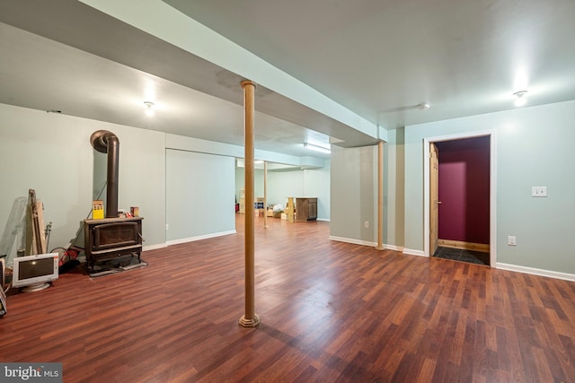 basement with a wood stove and dark wood-type flooring