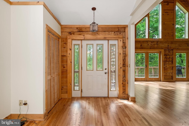 foyer entrance with wood walls and light wood-type flooring