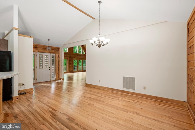 unfurnished living room with beam ceiling, light hardwood / wood-style flooring, high vaulted ceiling, and an inviting chandelier