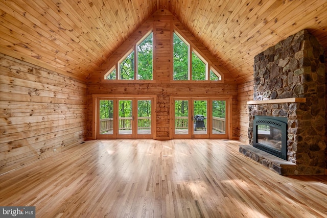 unfurnished living room featuring a stone fireplace, wood walls, high vaulted ceiling, and wood ceiling