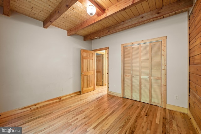 unfurnished bedroom featuring a closet, light hardwood / wood-style flooring, beamed ceiling, and wooden ceiling