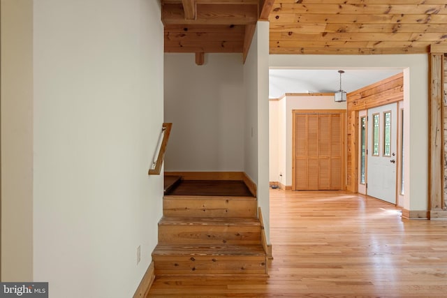 stairs with beam ceiling, wood ceiling, and hardwood / wood-style flooring