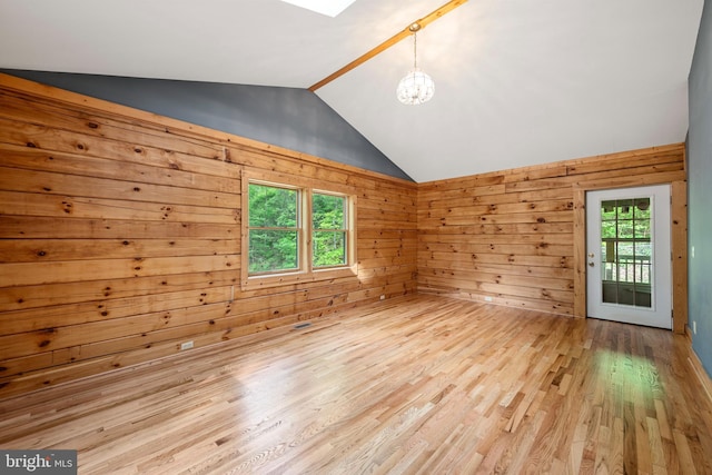 interior space featuring wooden walls, light hardwood / wood-style floors, vaulted ceiling, and an inviting chandelier