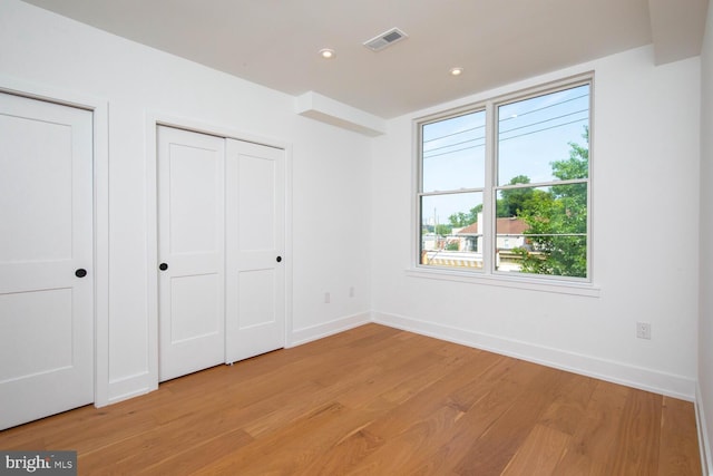 unfurnished bedroom featuring light wood-type flooring and multiple windows