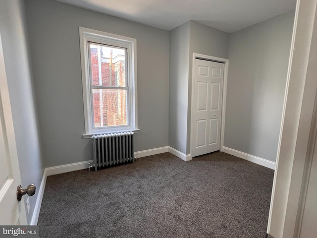 empty room with plenty of natural light, dark carpet, and radiator heating unit