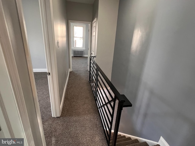 hall with dark colored carpet and radiator heating unit