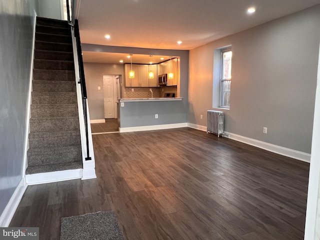 unfurnished living room featuring dark hardwood / wood-style flooring, sink, and radiator