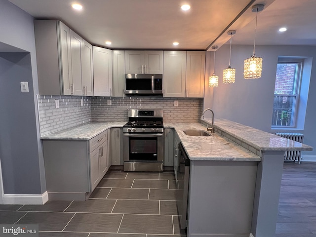 kitchen with gray cabinets, decorative light fixtures, radiator, stainless steel appliances, and kitchen peninsula