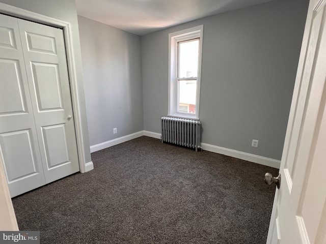 spare room with radiator and dark carpet