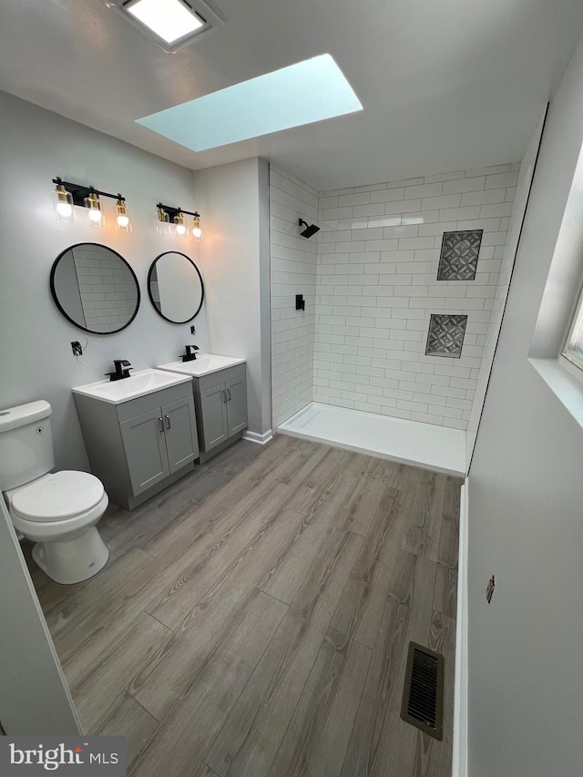 bathroom with hardwood / wood-style flooring, toilet, vanity, and a skylight