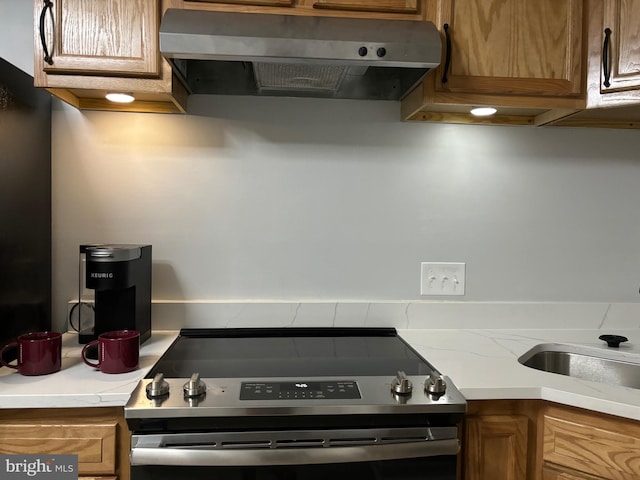 kitchen with stainless steel stove, sink, and wall chimney exhaust hood