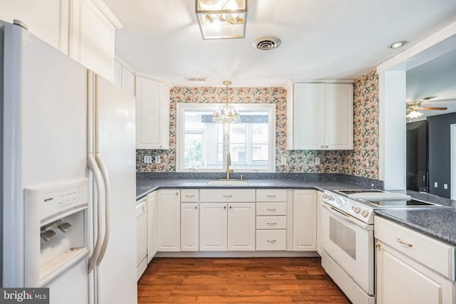 kitchen with hanging light fixtures, white appliances, hardwood / wood-style floors, sink, and ceiling fan