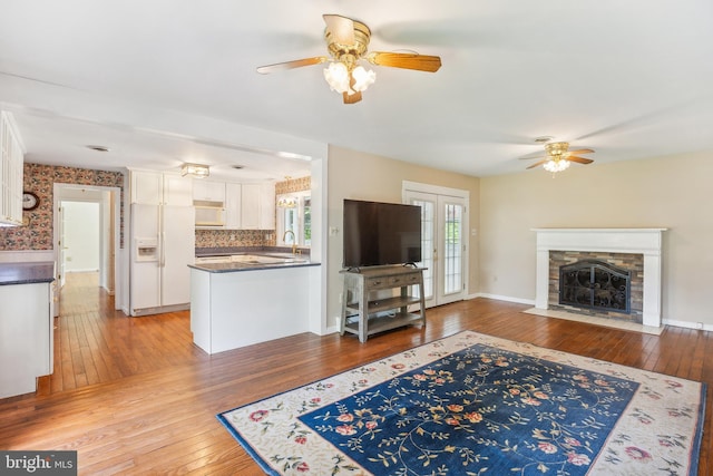 living room featuring a fireplace, ceiling fan, and light wood-type flooring