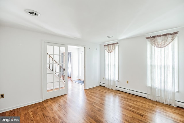 unfurnished room featuring light wood-type flooring and baseboard heating