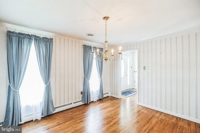 empty room featuring light hardwood / wood-style floors, a baseboard radiator, and an inviting chandelier