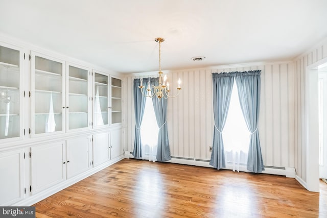 spare room featuring light hardwood / wood-style floors and an inviting chandelier