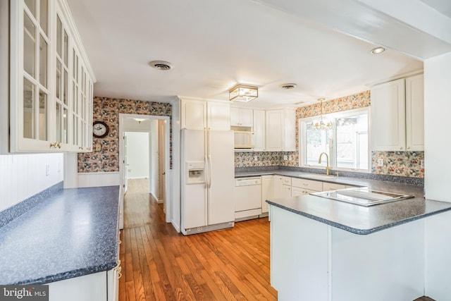 kitchen with sink, white appliances, tasteful backsplash, light wood-type flooring, and kitchen peninsula