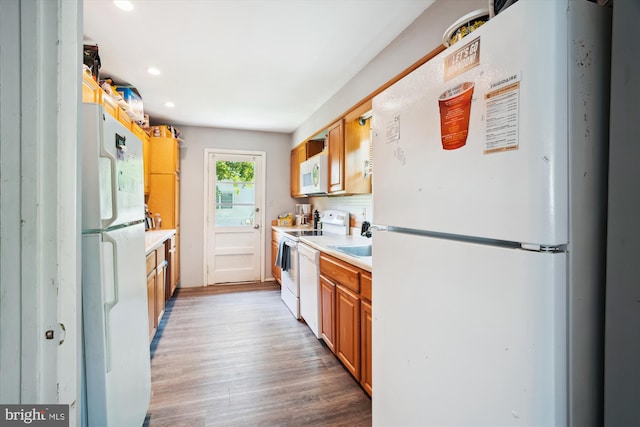 kitchen featuring backsplash, white appliances, and hardwood / wood-style flooring