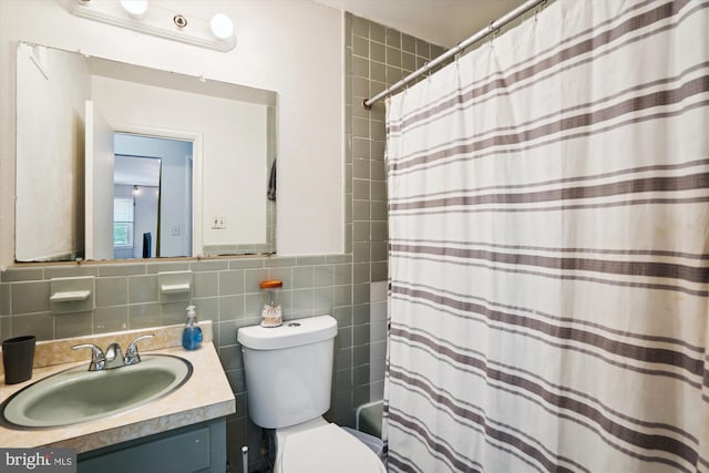 bathroom featuring vanity, toilet, and tile walls