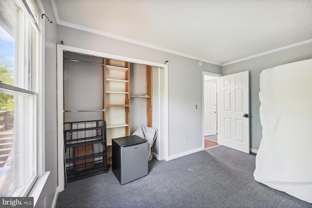 bedroom featuring dark carpet, stainless steel refrigerator, a closet, and crown molding