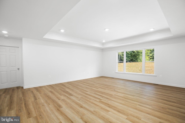 unfurnished room with baseboards, light wood-style flooring, recessed lighting, crown molding, and a raised ceiling