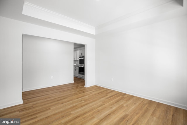 unfurnished room featuring light wood-style flooring, baseboards, and ornamental molding