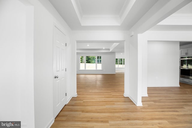 hall with a raised ceiling, light wood-style floors, and ornamental molding