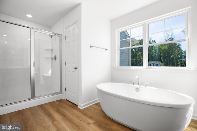 bathroom with a shower stall, baseboards, wood finished floors, recessed lighting, and a freestanding tub