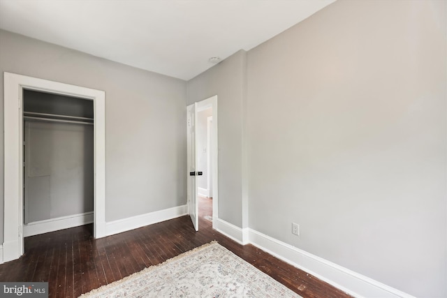 bedroom with dark hardwood / wood-style flooring and a closet