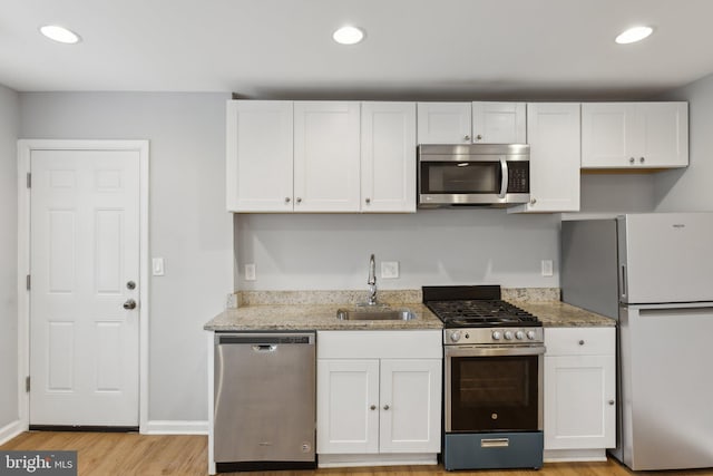 kitchen with light stone counters, stainless steel appliances, sink, and white cabinets