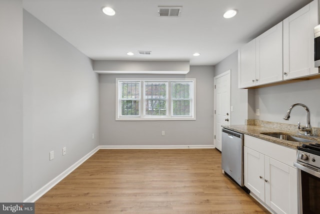 kitchen with sink, light stone countertops, white cabinets, and appliances with stainless steel finishes